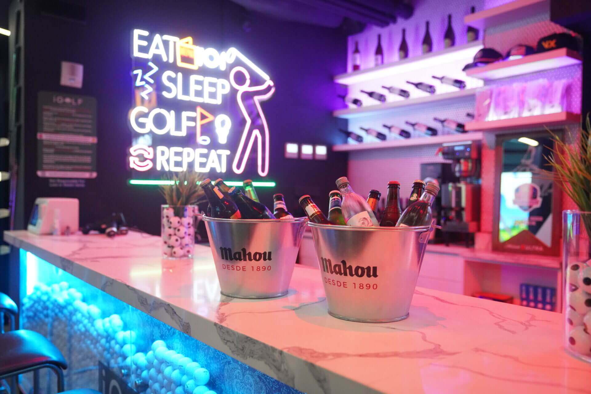 Neon-lit bar with 'Eat Sleep Golf Repeat' sign and buckets of bottled drinks